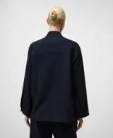 Sobrecamisa de mujer color azul marino con textura sutil de rayas verticales. Presenta un corte amplio (boxy fit), cuello mao (cuello tira) y manga larga con puño. Cierre frontal oculto por solapa.