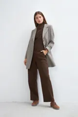 Saco corto entallado de lana fina, con cuello solapa, manga larga y cierre frontal con botones. Presenta un diseño clásico con textura de espiga en tonos tierra.