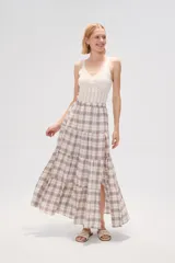 Falda larga de algodón con diseño a cuadros en tonos beige, blanco, marrón y celeste. Presenta un diseño escalonado con volados y una abertura lateral pronunciada.