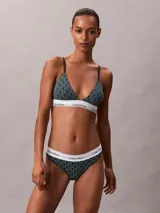 Bombacha tipo colaless Calvin Klein de tiro alto, confeccionada en una mezcla de algodón y modal. Presenta un estampado geométrico con el logo de la marca y una banda elástica blanca en la cintura con el nombre de la marca repetido.