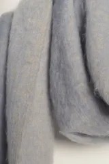 Bufanda manta de tejido suave y peluche, color celeste claro, con flecos largos en los extremos de color beige.