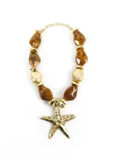 Collar con cuentas facetadas efecto carey en tonos marrones, cuentas metálicas doradas y un gran dije colgante en forma de estrella de mar con acabado texturizado.