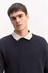 Sweater de punto texturizado color azul marino, de manga larga, con cuello polo en color beige contrastante.