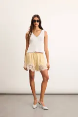 Musculosa de punto color blanco crudo, con escote en V y terminaciones con bordado artesanal amarillo.