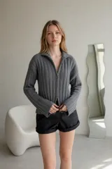 Sweater de punto acanalado color crema, con cuello alto y cierre frontal doble bidireccional, de manga larga y ajuste entallado.
