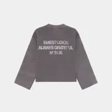Sweater de punto oversize gris oscuro, con cuello redondo y texto bordado en la espalda que dice "EMESTUDIOS ALWAYS GRATEFUL N5135".