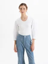 Top de tejido de punto acanalado en color blanco, con cuello redondo y mangas tres cuartos de tela plana con volumen. Presenta un diseño ajustado al cuerpo que contrasta con la estructura de las mangas.