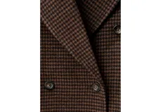 Abrigo largo cruzado de lana con estampado de cuadros tipo houndstooth en tonos marrones, solapas de muesca y doble botonadura frontal.