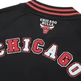 Campera negra con detalles en rojo y blanco, con cierre frontal y bolsillos laterales. Presenta el logo de los Chicago Bulls en el pecho y letras en el brazo izquierdo.