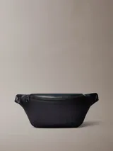 Riñonera Calvin Klein negra de poliuretano, diseño waist bag con cierre de cremallera superior, correa ajustable y monograma CK grabado en la parte delantera.