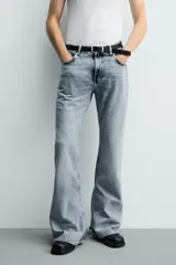 Jeans flare fit de tiro medio, confeccionados en denim de algodón color azul con efecto deslavado. Diseño ajustado en la parte superior y abierto en campana desde la rodilla, con cinco bolsillos y cierre frontal con cremallera y botón.