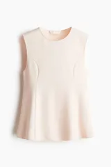 Musculosa sin mangas color rosa pálido, con cuello redondo y paneles laterales que crean un efecto peplum acampanado en la parte inferior.