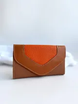 Billetera de cuero color naranja y marrón con cierre de broche y monedero externo.
