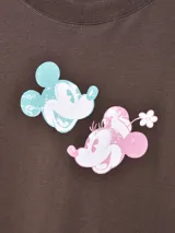 Remera oversize de manga corta color marrón oscuro, con diseño estampado de Mickey y Minnie Mouse al frente en tonos celeste y rosado.