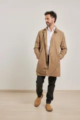 Gabardina color beige de algodón, con cuello clásico, cierre frontal con botones, dos bolsillos de ribete delanteros, bolsillo interior con botón y abertura posterior en el bajo.