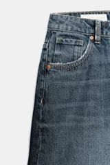 Bermuda baggy de denim azul con tiro medio, trabillas para cinturón y diseño de cinco bolsillos. Presenta cierre frontal con cremallera y botón metálico.