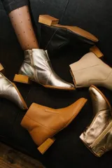 Botín de cuero dorado con punta fina y taco bajo cuadrado de madera.