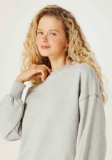 Buzo color crema de algodón, de corte holgado, con cuello redondo y mangas largas. Puños y ruedo acanalados.