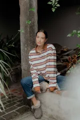 Buzo de algodón y elastano con cuello polo marrón y botones. Diseño de rayas horizontales en blanco, marrón y naranja. Mangas largas con puños naranjas.