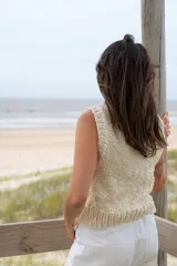 Chaleco tejido de punto en color crudo, con cuello alto y diseño sin mangas. Presenta una textura de punto grueso y corte recto.