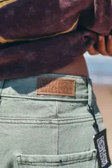 Pantalon de denim estilo wide leg en color verde lavado, con corte holgado y diseño de tiro medio. Presenta costuras reforzadas y detalle de marca bordado verticalmente en la pierna.