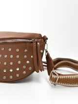 Riñonera color camel con tachas plateadas y correa de tela con diseño geométrico en tonos beige y blanco.