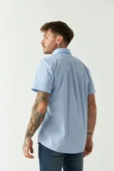 Camisa de manga corta con estampado de cuadros vichy en azul y blanco. Presenta cuello con botones, cierre frontal con botones y logo bordado en el pecho.