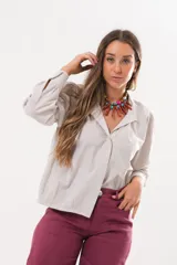 Camisa beige a rayas finas de manga larga, con cuello camisero y cierre frontal oculto.