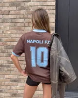 Camiseta de fútbol color marrón con cuello en V y detalles en celeste, inspirada en el Napoli F.C., con diseño de mangas cortas y sponsors impresos en el frente.