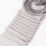 Cinto elástico plateado con hebilla metálica entrelazada compuesta por una pieza circular y una romboidal con textura estriada.