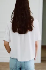 Camisa de algodón de corte recto con cuello solapa, manga corta y cierre frontal con botones ocultos. Presenta un diseño con pechera y una corbata negra extraíble a contraste.