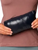 Campera puffer ultraligera de mujer, con diseño acolchado horizontal, cierre frontal completo y capucha integrada. Confeccionada en tejido ripstop reciclado con aislamiento de plumón de alta capacidad térmica.