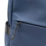 Mochila azul de símil cuero con acabado aterciopelado, asa de mano textil, acceso principal con cierre, dos compartimentos internos (uno acolchado para notebook), bolsillo interno con cierre, dos bolsillos externos con cierre y dos bolsillos laterales sin cierre.