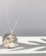 Collar plateado con dije esférico texturizado con incrustaciones de gemas de colores.