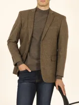 Blazer marrón corte slim, confeccionado en tejido con mezcla de lana. Cuello con solapas, manga larga con puño abotonado, bolsillos de solapas en cadera, abertura en espalda, cierre frontal de botonadura y coderas en suede chocolate.