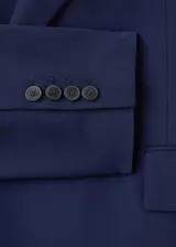 Blazer azul marino de estilo sastrero, corte recto, con cuello pico y solapas de muesca. Cuenta con dos bolsillos con solapa en los laterales y cierre frontal de doble botonadura.