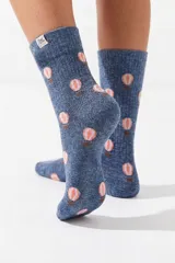 Medias color azul melange con estampado de globos aerostáticos en tonos rosados y marrones, y etiqueta lateral con logo.