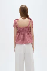Musculosa de lino con estampado de cuadros vichy en rojo y blanco, escote recto y tirantes anchos con lazos para anudar en los hombros.