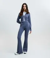 Pantalón flare de tiro alto con cintura ancha, confeccionado en tejido de microfibra. Presenta un corte ceñido en caderas y muslos con apertura acampanada desde la rodilla.
