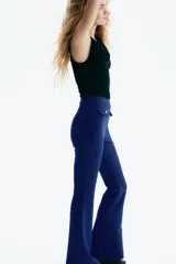 Pantalón acampanado de punto roma, color azul, con elástico oculto en la cintura y solapas de bolsillo decorativas con botón dorado en el frente.