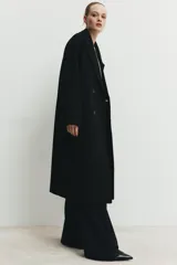 Abrigo largo de corte oversize con cuello de solapa, manga larga y cierre frontal cruzado con botones. Cuenta con bolsillos delanteros.