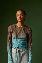 Top de mangas largas con estampado floral en tonos azules, verdes y naranjas. Tiene un cordón ajustable en el centro que crea un efecto drapeado.