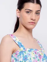 Top blanco con estampado floral en tonos naranja y lila, de corte cropped y breteles anchos.