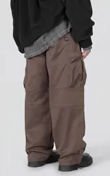 Pantalón cargo marrón de calce regular, confeccionado en textil técnico pesado. Posee cintura con cordón ajustable, bolsillos cargo de gran tamaño en los laterales y puños ajustables con tancas en los tobillos.
