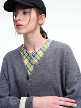 Cardigan de punto color marrón con textura jaspeada, escote en V, cierre frontal con botones y diseño de hombros caídos.