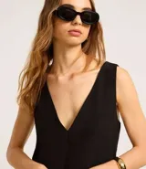 Vestido corto negro de crepé con escote en V tanto en la parte delantera como en la trasera. Tiene bolsillos delanteros con botones dorados.