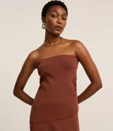 Blusa slim texturizada de color marrón, sin breteles, con escote recto, laterales fruncidos y bajo asimétrico.