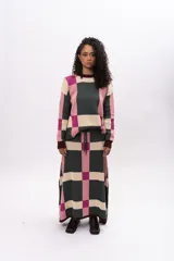 Pollera midi de tejido de punto con diseño geométrico de cuadros en tonos verde, rosa y beige. Presenta cintura elástica con cordón de ajuste y aberturas laterales en el ruedo.