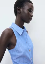 Vestido midi celeste a rayas verticales, sin mangas, con cuello camisero, cierre frontal con botones y cinturón forrado con hebilla.