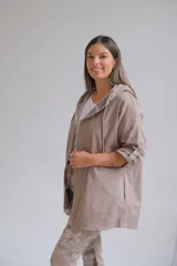 Campera tipo parka liviana color visón, con cierre frontal, capucha con cordones ajustables y mangas 3/4 con detalle de trabilla. Presenta un diseño holgado y casual.